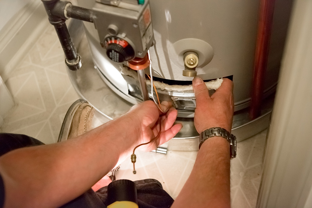 Plumber performing maintenance on a water heater in a West Chester home