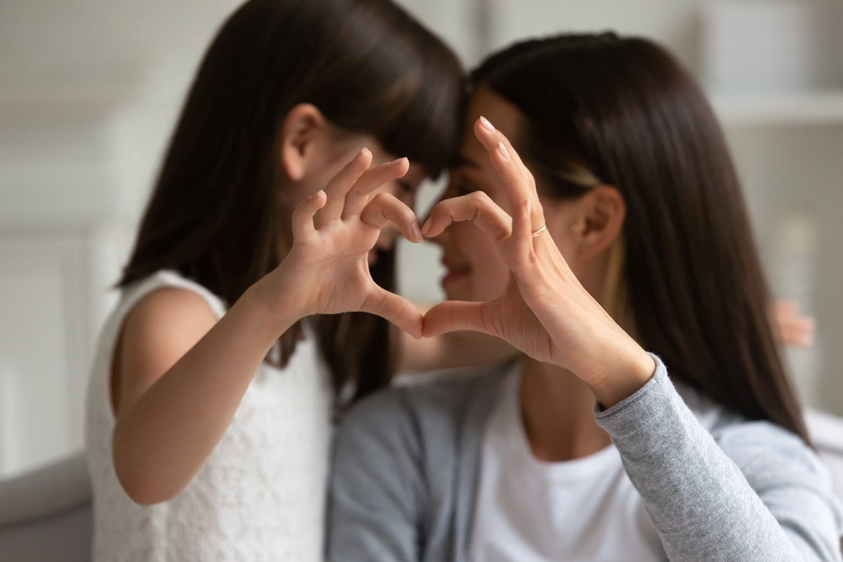 Mom with daughter with hands forming a heart